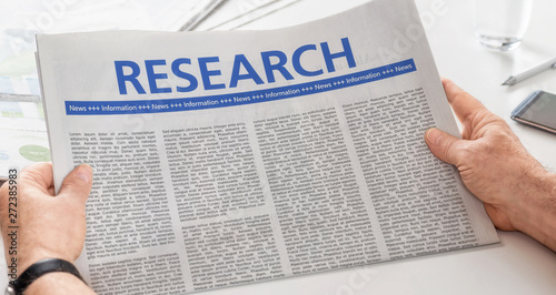 Man reading newspaper with the headline Research
