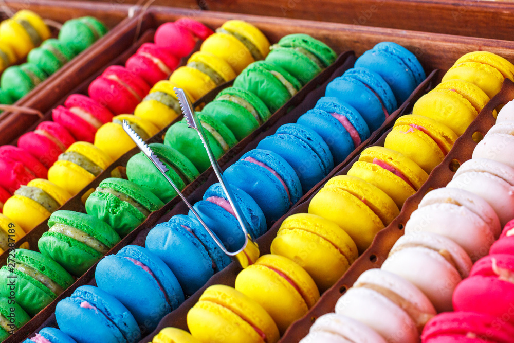 Colorful macaroons. Traditional sweets with silver tongs