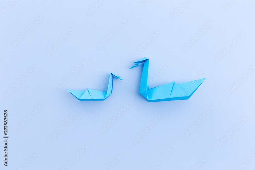 Fototapeta premium A swan with child of paper on a blue background, origami