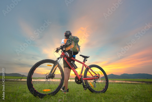 Woman cyclist bicycle paused riding on the meadow field, looking for forward ahead possibility cross the lake, adventure woman riding mountain bike alone in meadow at countryside