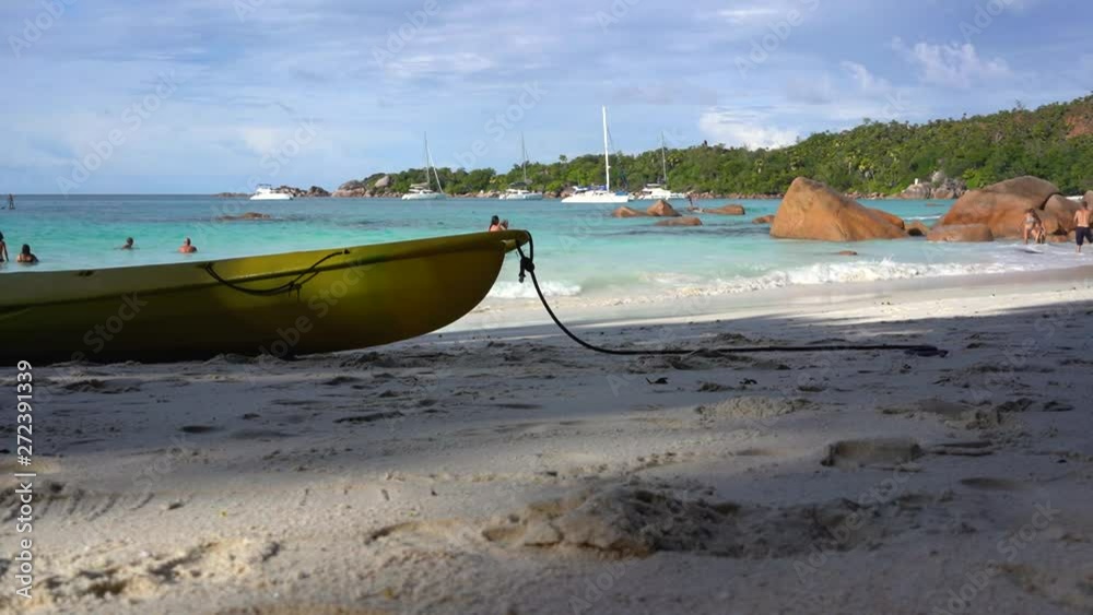 Seychelles. Praslin Island. Beautiful view of the stony coast of the island located in the Indian Ocean. Boat in the foreground. People bathe in the sea.
