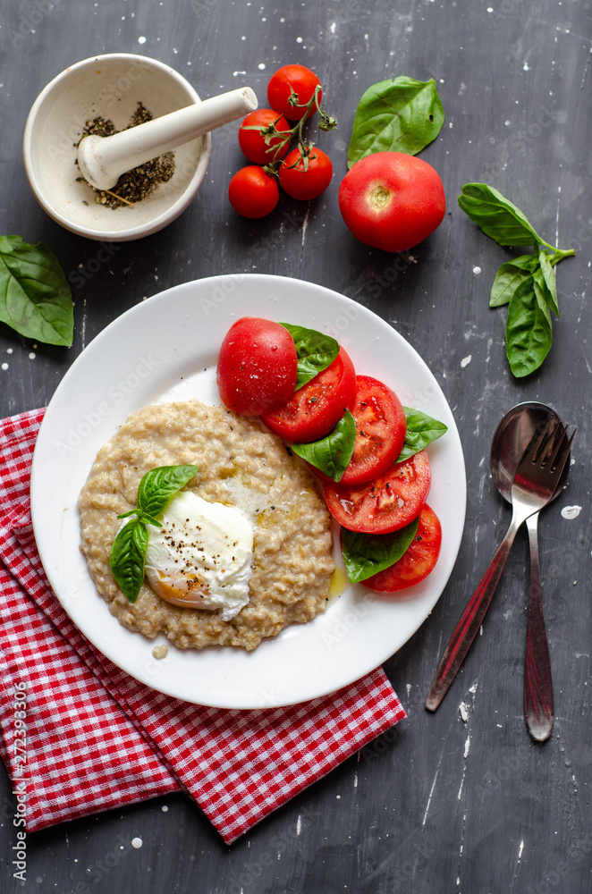 oatmeal with poached egg, tomatoes and basil. fresh tasty proper nutrition meal. healthy food for breakfast oatmeal with poached egg, tomatoes and basil. fresh tasty proper nutrition meal. healthy food for breakfast
