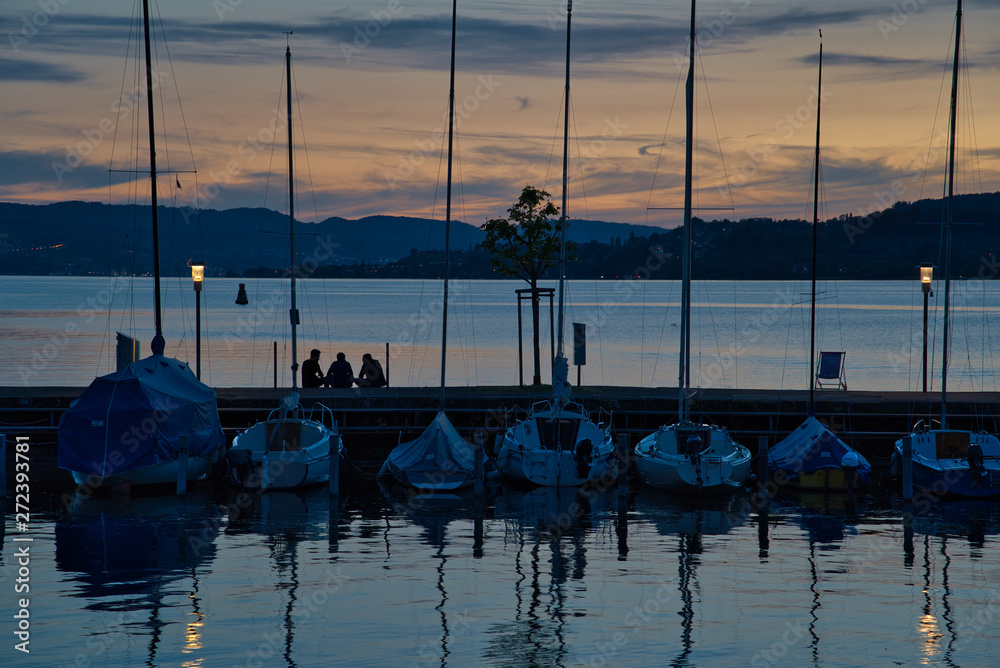 Menschen am See mit Segelbooten