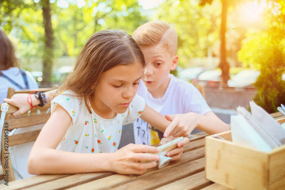 Two kids playing with mobile phone at terrace, little boy and girl addicted to modern technology Two kids playing with mobile phone at terrace, little boy and girl addicted to modern technology