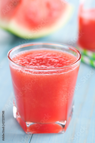 Refreshing watermelon juice on blue wood (Selective Focus, Focus on the front of the glass rim)