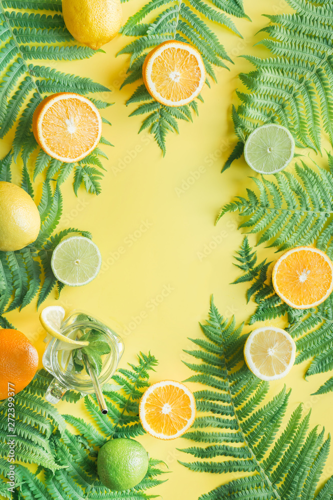 Tropical friuts, orange, lemon, lime on yellow and fern leaves. Top view. Summer concept. Tropical friuts, orange, lemon, lime on yellow and fern leaves. Top view. Summer concept.