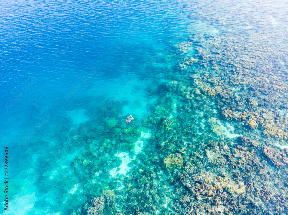 Fototapeta premium Aerial top down people snorkeling on coral reef tropical caribbean sea, turquoise blue water. Indonesia Banyak Islands Sumatra, tourist diving travel destination.