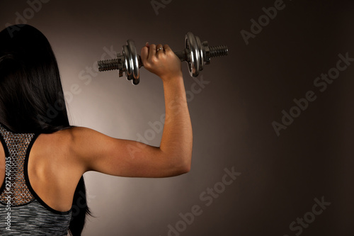 Fototapeta Naklejka Na Ścianę i Meble -  Active young woman wprkout with dumbbells in a fitness gym