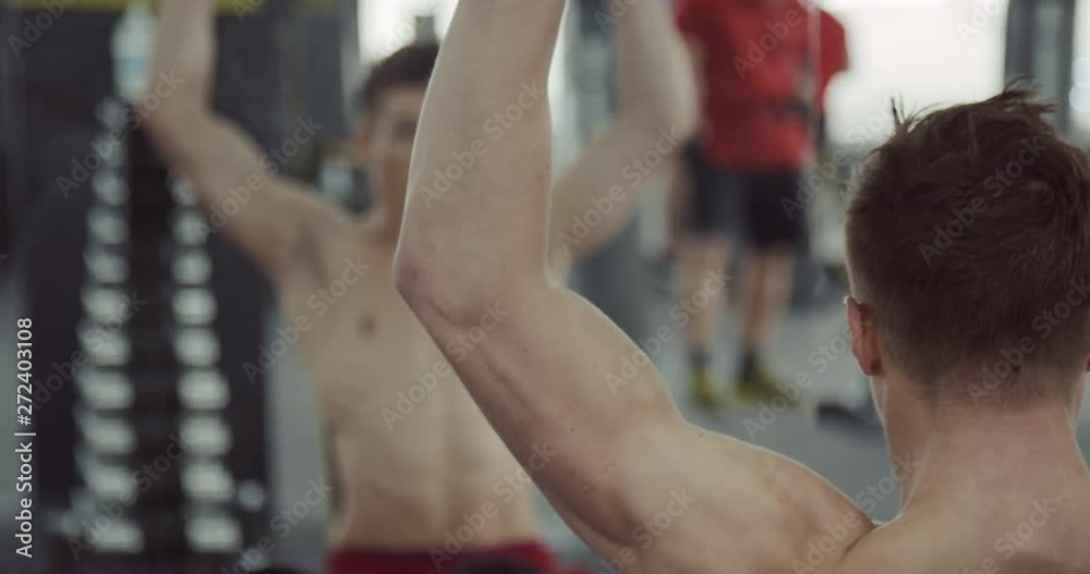 Croped view of atleth shakes his biceps with dumbbells in front of the mirror, view is reflected in the mirror