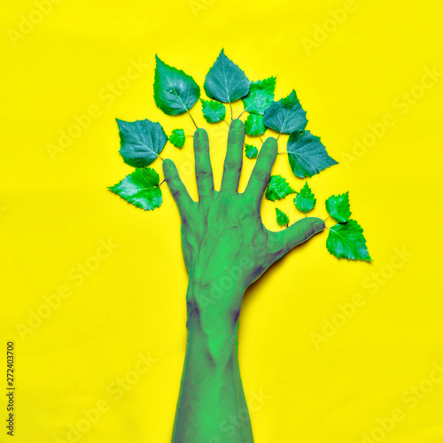 Environment concept. Hand with leaves in the form of a tree on a yellow background. photo