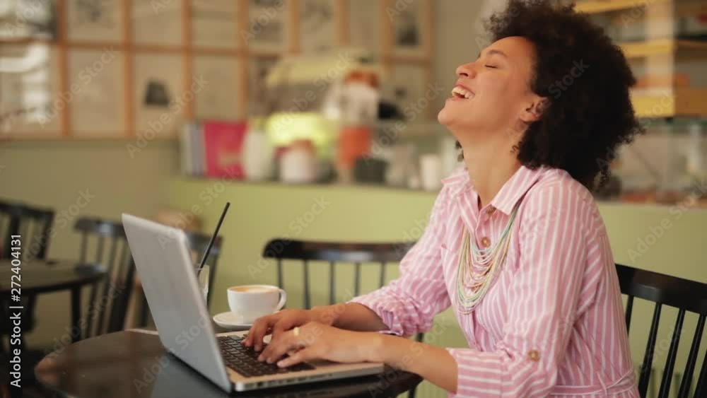 Smiling mixed race businesswoman sitting in pastry shop and using laptop. Smiling mixed race businesswoman sitting in pastry shop and using laptop.