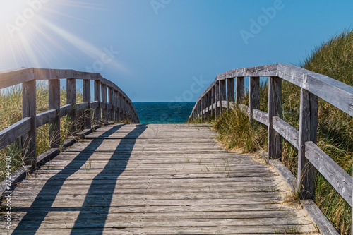 A wooden pathway crossing the dunes. The way leads to the beach on a beautiful summer day.