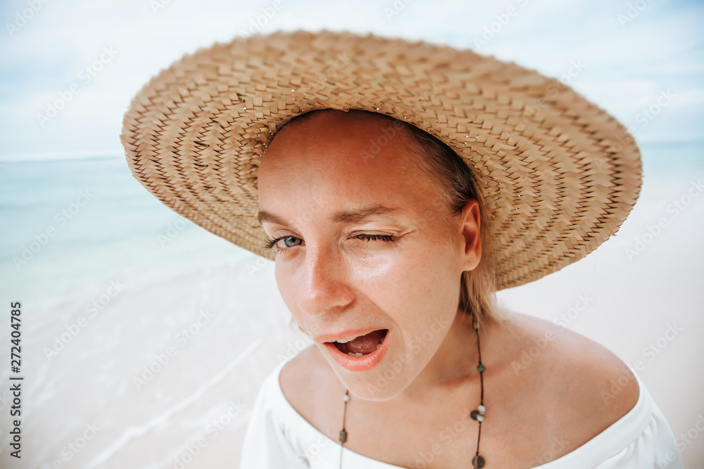 Portrait of funny girl and straw hat on white beach