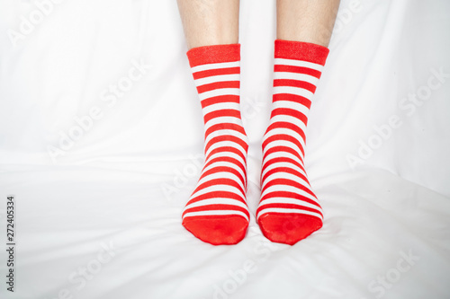 Women's legs in socks colors alternating, side stand on white fabric floor.