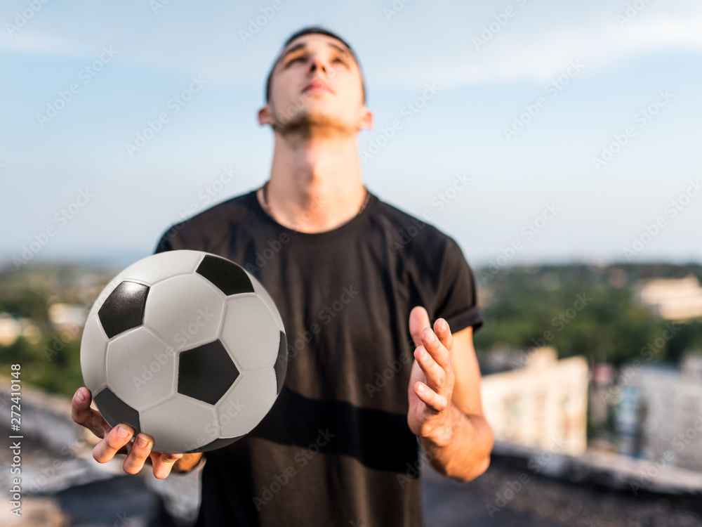 Man playing with ball outdoors on the roof on the background of the city Man playing with ball outdoors on the roof on the background of the city