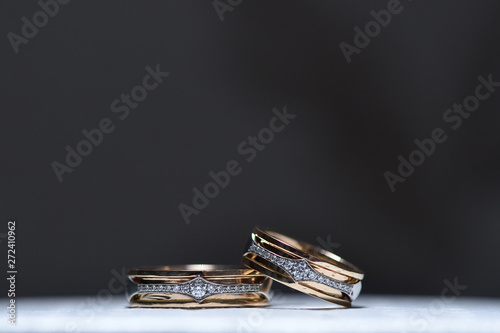 Beautiful wedding gold diamond rings lie on a white box surface. Close-up, macro photography