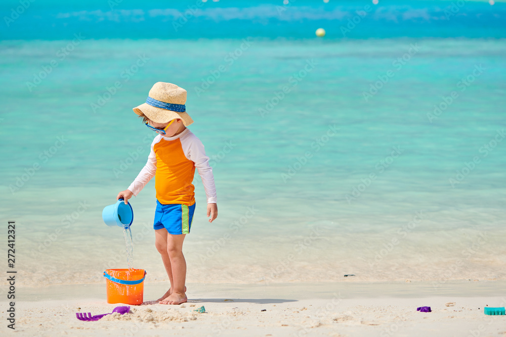 Three year old toddler boy playing with beach toys on beach. Summer family vacation at Maldives. Three year old toddler boy playing with beach toys on beach. Summer family vacation at Maldives.
