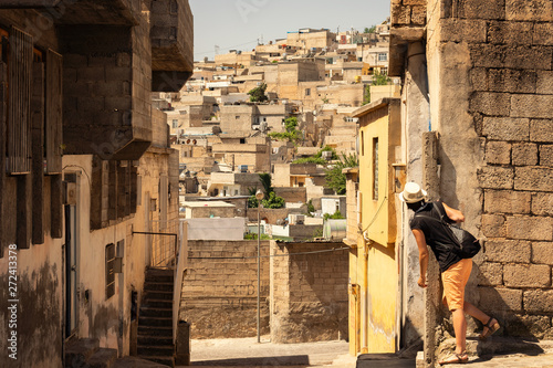 Young tourist girl looking behind the corner over the crowded neighbourhood in Turkish city of Sanliurfa. Old houses on the steep hill. photo