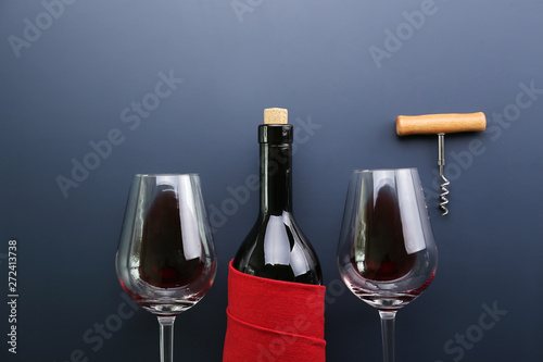 Vintage bottle of red wine with blank matte black label, corkscrew on graphite gradient table background. Expensive bottle of cabernet sauvignon concept. Copy space, top view, flat lay.