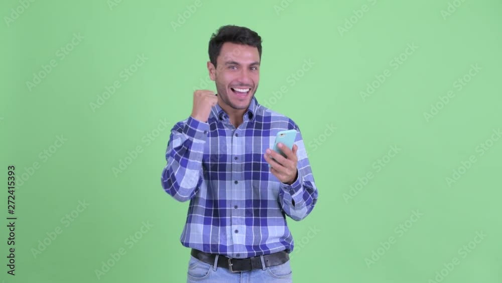 Happy young Hispanic man using phone and getting good news Happy young Hispanic man using phone and getting good news