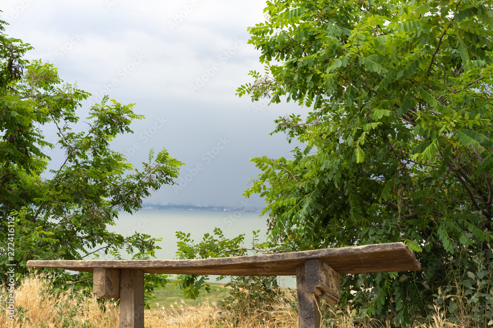 Storm clouds over the sea and the city.Old wooden bench against the background of the sea.