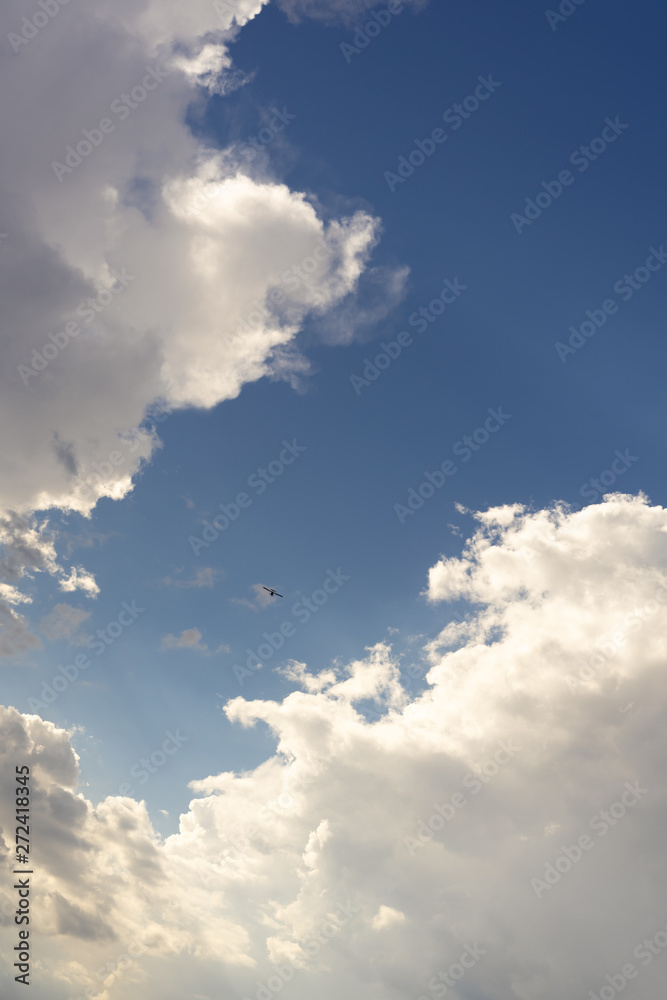 Obraz premium Beautiful blue sky and clouds. Creative vintage background. Very small plane on a background of clouds.