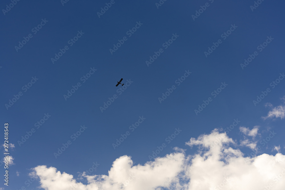 Beautiful blue sky and clouds. Creative vintage background. Very small plane on a background of clouds.