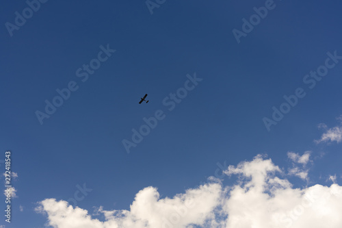 Beautiful blue sky and clouds. Creative vintage background. Very small plane on a background of clouds.