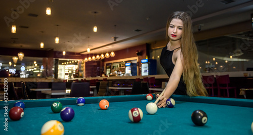 Canvas Print Young and beautiful woman in pub playing billiard