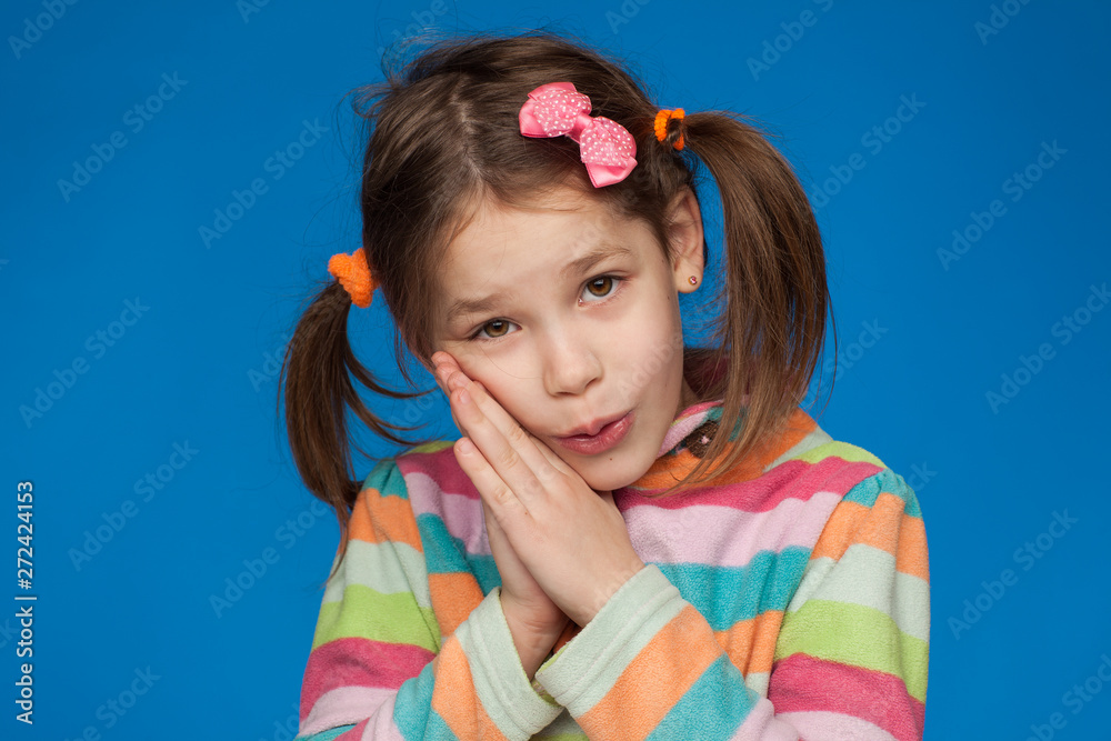 Portrait of an emotional girl of five years in a striped sweater on a blue background Portrait of an emotional girl of five years in a striped sweater on a blue background