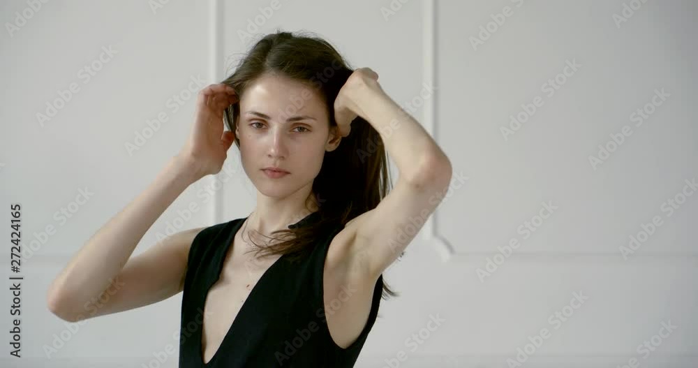 young slender woman is touching her hair and looking at camera, posing in studio young slender woman is touching her hair and looking at camera, posing in studio