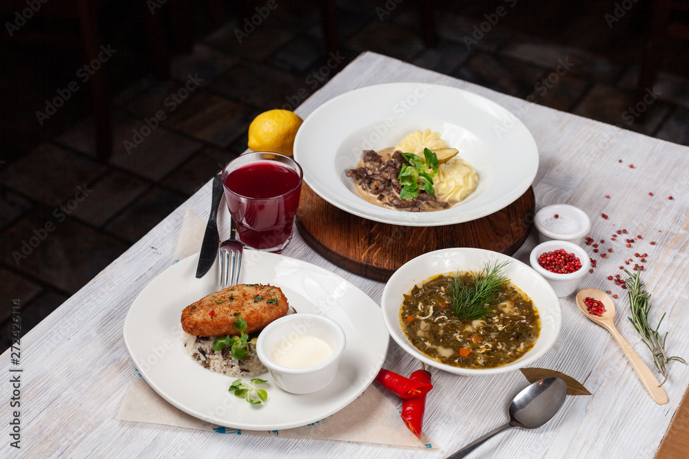 Top view of a three course set menu: beef stroganoff with mashed potatoes, turkey cutlet with rice and hot sorrel soup Top view of a three course set menu: beef stroganoff with mashed potatoes, turkey cutlet with rice and hot sorrel soup