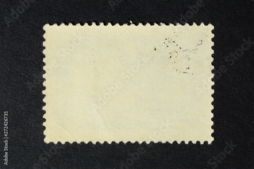 Blank vintage postage stamp on black background. Mockup with perforations for your picture text or design.