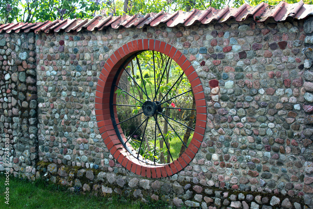 Stone garden fence with round window shaped like a wheel