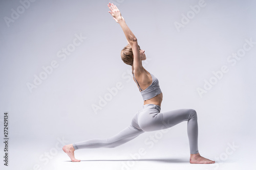 Sporty concentrated woman in sportswear practicing yoga, standing in anjaneyasana pose, attractive girl doing Horse rider exercise, working out at home or in yoga studio