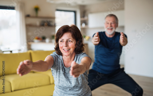 A senior couple indoors at home  doing exercise indoors.