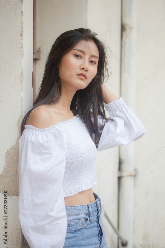 Portrait of thai adult beautiful girl White shirt blue jeans relax and smile Portrait of thai adult beautiful girl White shirt blue jeans relax and smile