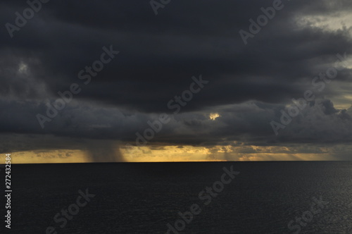 Dark clouds with rain on the ocean during sunset. Seychelles
