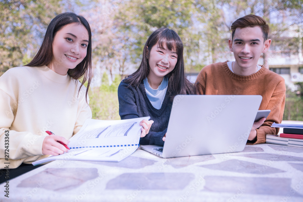 Group Of University Students asian sitting on the green grass Working and reading Outside Together in a park Group Of University Students asian sitting on the green grass Working and reading Outside Together in a park