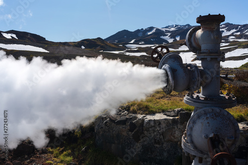 View of emission mineral thermal steam-water mixture from geological well in geothermal deposit area, geothermal power plant on slope of active volcano. Eurasia, Russian Far East, Kamchatka Peninsula.