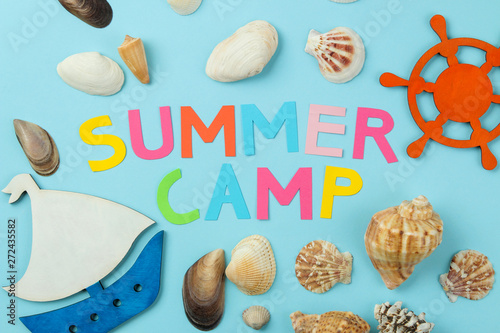 Text SUMMER CAMP from multicolored paper letters and sea scenery against a bright blue background. top view. flat lay