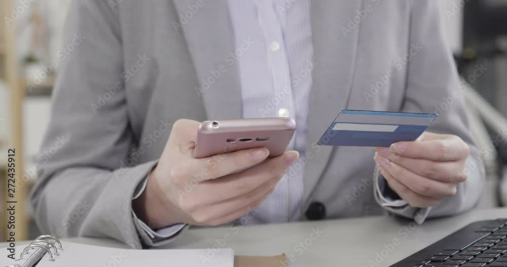 Close up of asian woman hands holding mobile phone and credit card. young businesswoman checking account balance using online banking application on cellphone in modern office sitting at desk. Close up of asian woman hands holding mobile phone and credit card. young businesswoman checking account balance using online banking application on cellphone in modern office sitting at desk.