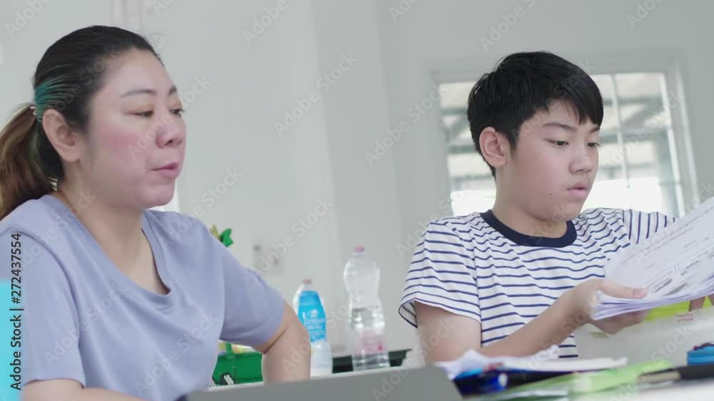 The strict Asian mother is checking the son's education. The son was found guilty of homework. By the mother who cares about the child's learning The strict Asian mother is checking the son's education. The son was found guilty of homework. By the mother who cares about the child's learning