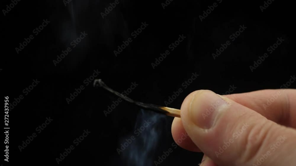 Smoke from Match lighting and burning till the end and finally disappears from the flame on black background. The match lights up, burns and goes out. Burning match stick lights and then blown out.