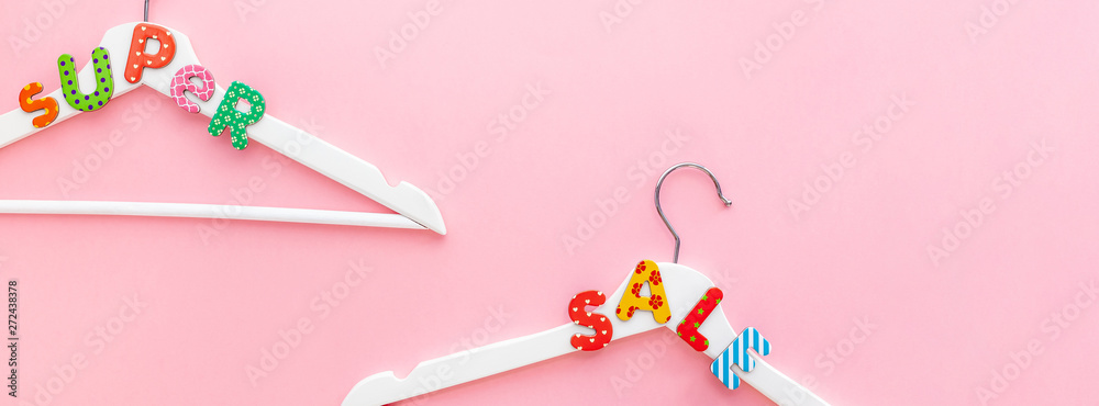 White hangers with sale text on pink background White hangers with sale text on pink background