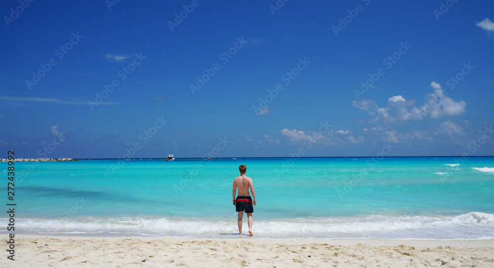 Man going to swim in Caribbean sea, Cancun beach, Mexico.