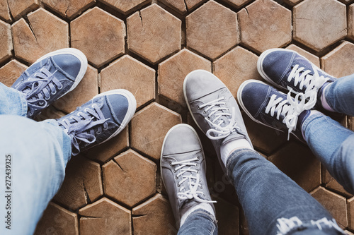 Three pairs of woman’s and child’s legs; wooden background. photo