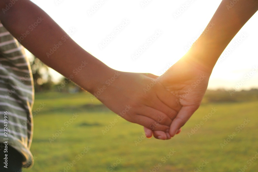 Children hold hands to show friendship, shoot blurred images, golden yellow light in the evening Children hold hands to show friendship, shoot blurred images, golden yellow light in the evening