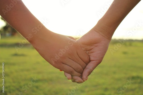 Children hold hands to show friendship, shoot blurred images, golden yellow light in the evening
