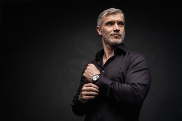 Middle-aged good looking man posing in front of a black background with copy space.